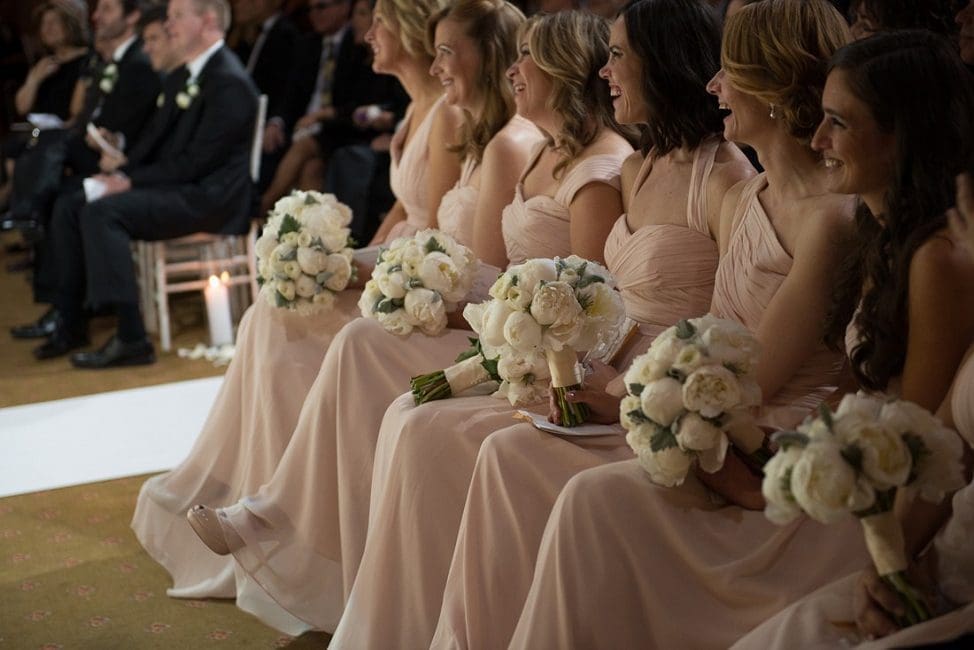 A group of bridesmaids sitting in a row with their bouquets.