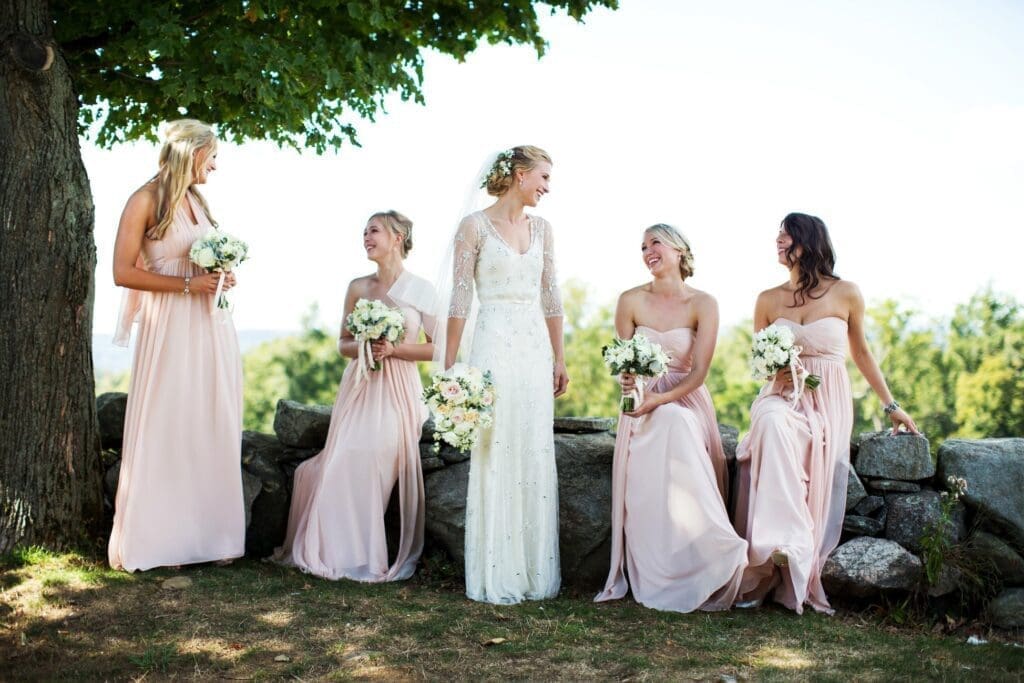 A bride and her bridesmaids are standing in front of a stone wall.