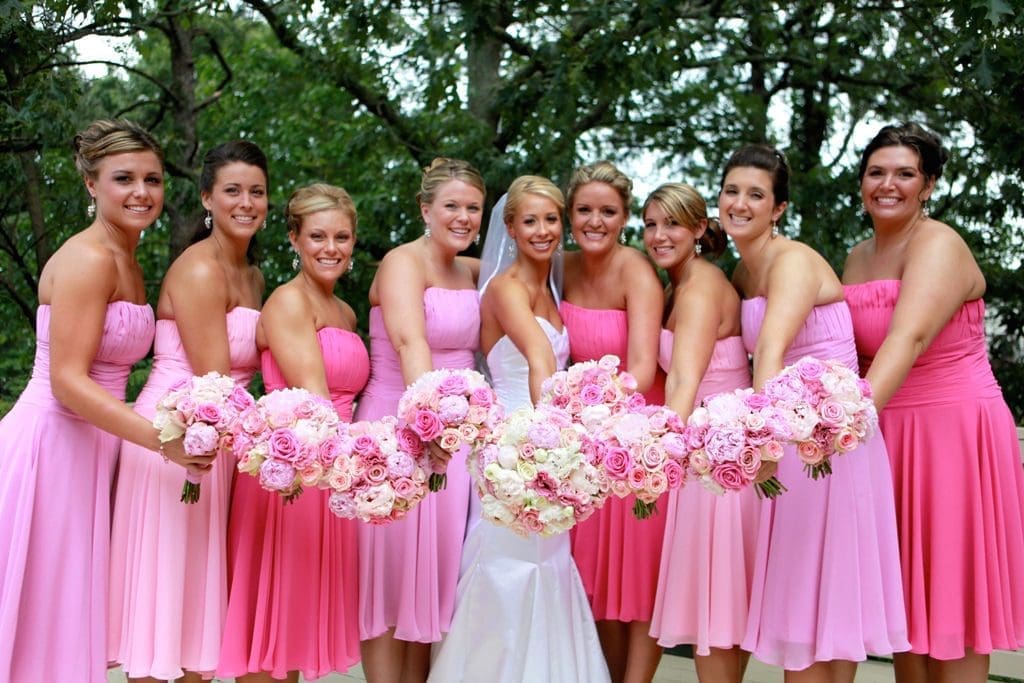 A group of bridesmaids in pink dresses holding bouquets.