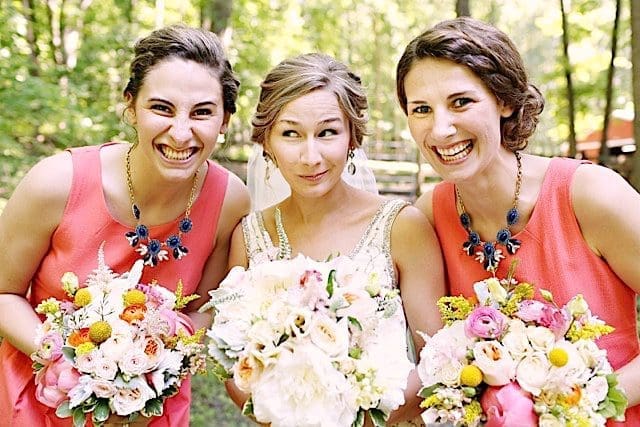 Three bridesmaids are holding bouquets in the woods.