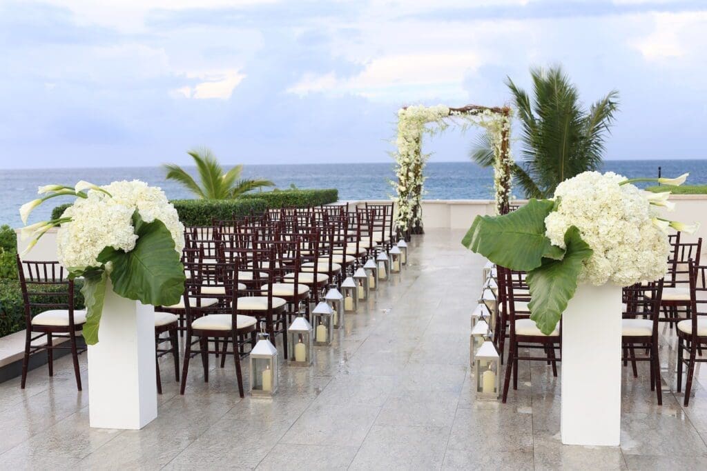 A wedding ceremony set up with white chairs and flowers.