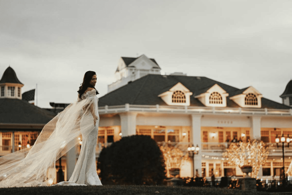 A bride standing in front of a hotel at dusk.