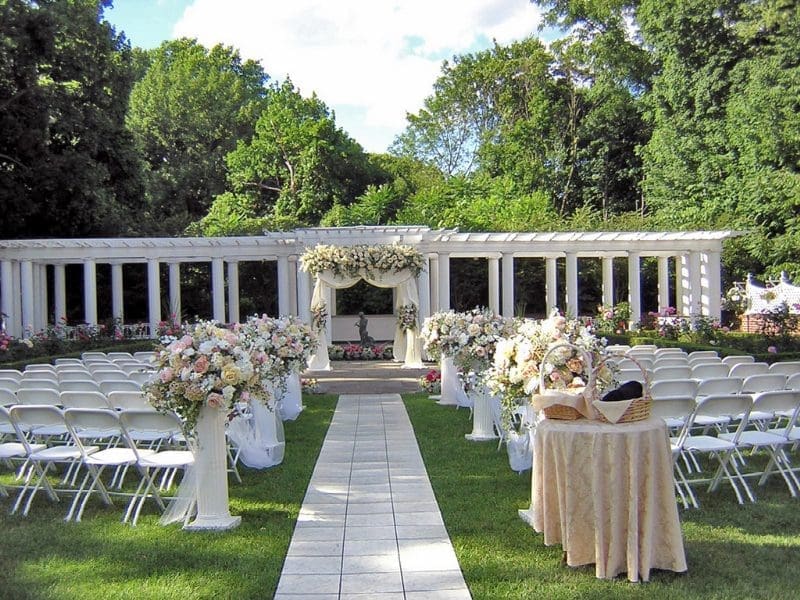 An outdoor wedding ceremony set up with white chairs and flowers.