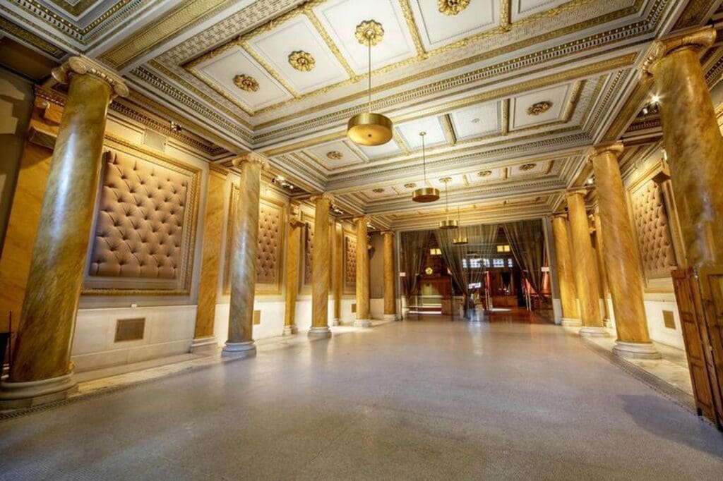 The lobby of a large building with gold pillars and columns.