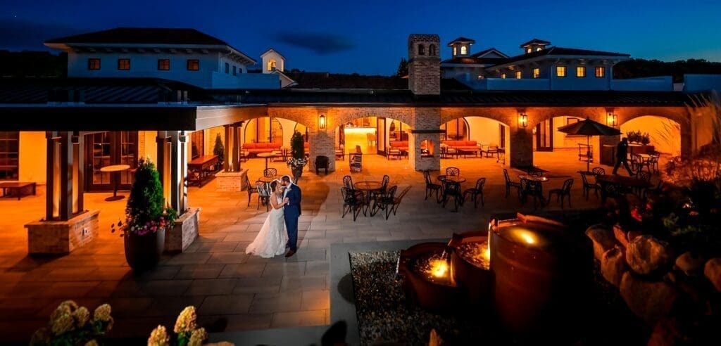A bride and groom standing in the courtyard at night.