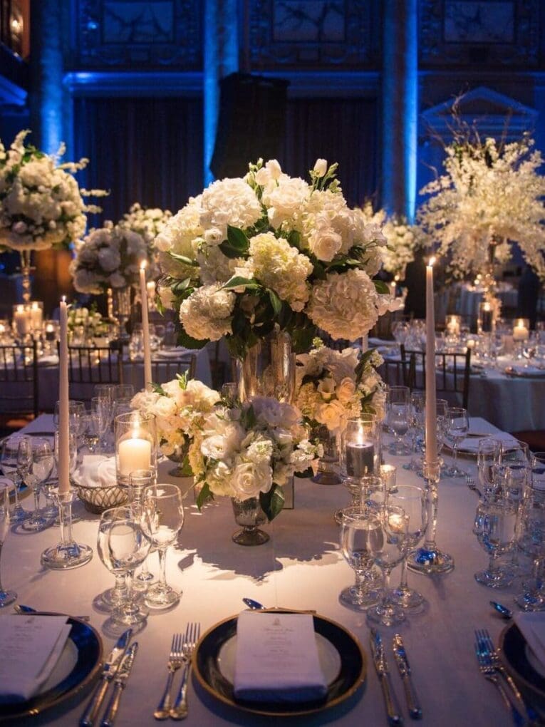 A white and blue table setting with candles and flowers.