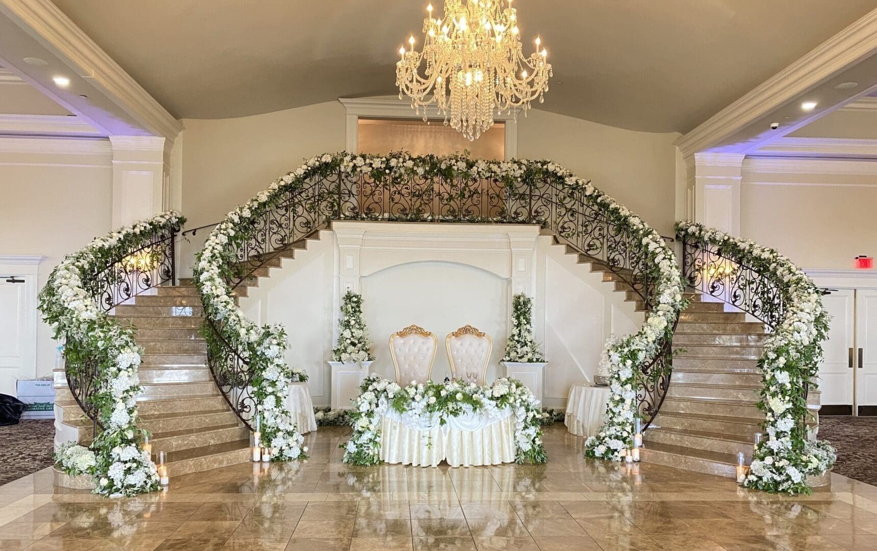 A wedding ceremony set up with white flowers and a chandelier.