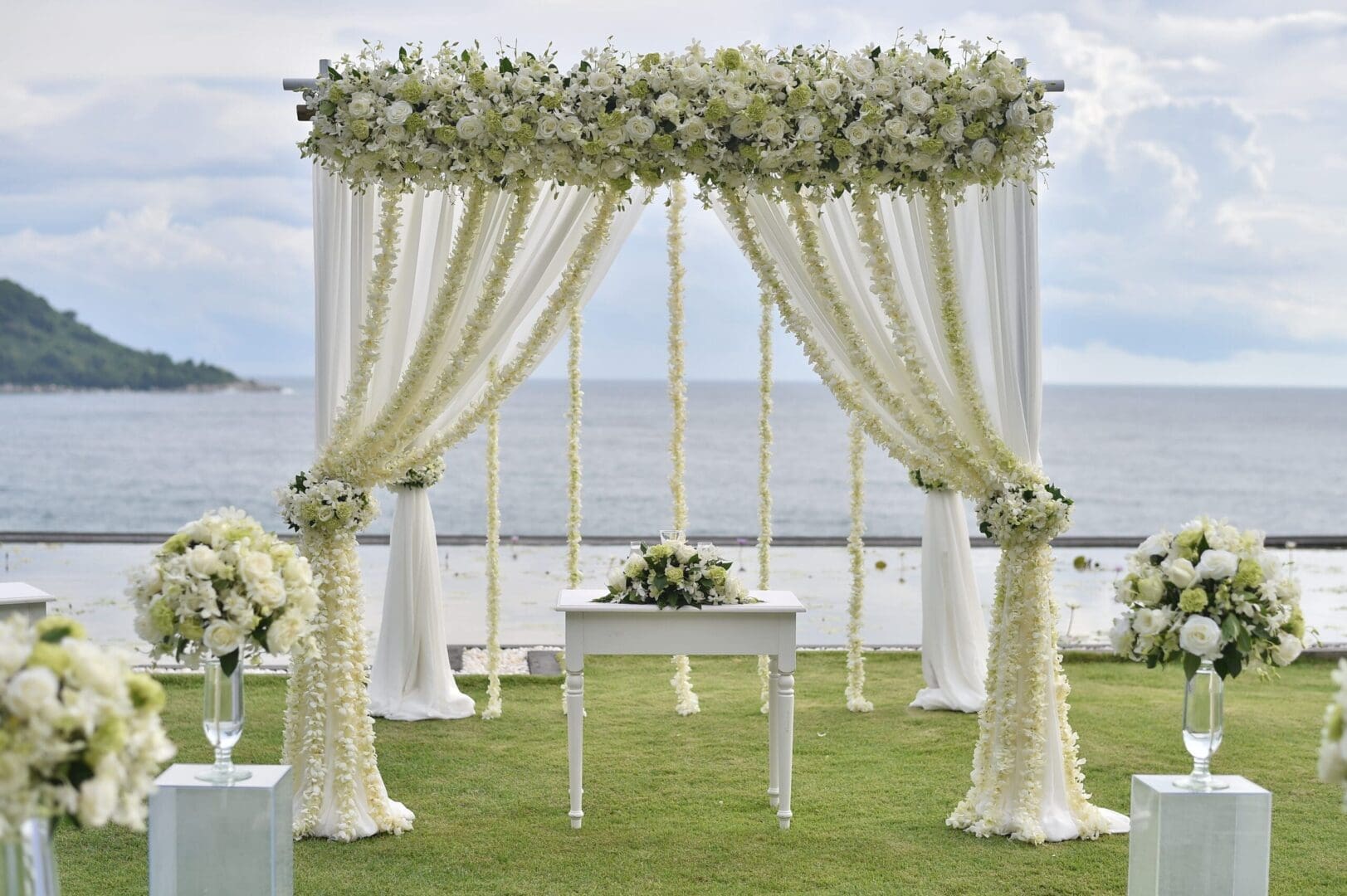 A wedding ceremony set up with white flowers and a view of the ocean.