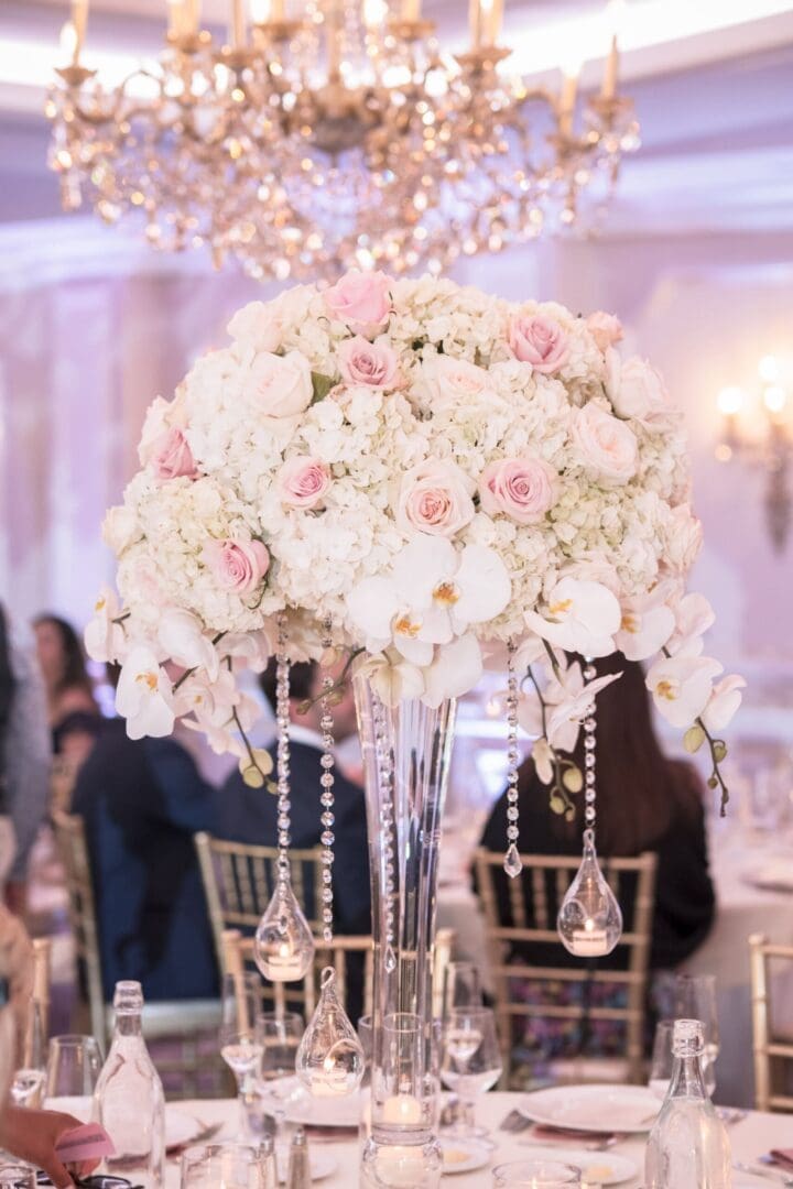 A wedding reception with elegant white flowers and a stunning chandelier, creating a breathtaking tablescape.