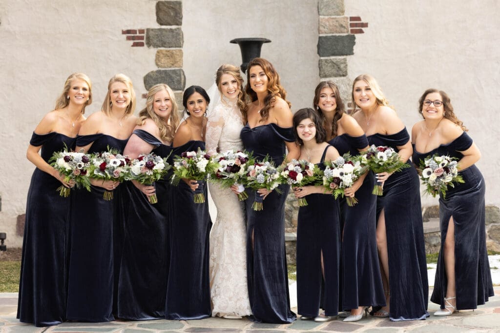 Bridesmaids in navy velvet dresses posing for a photo.