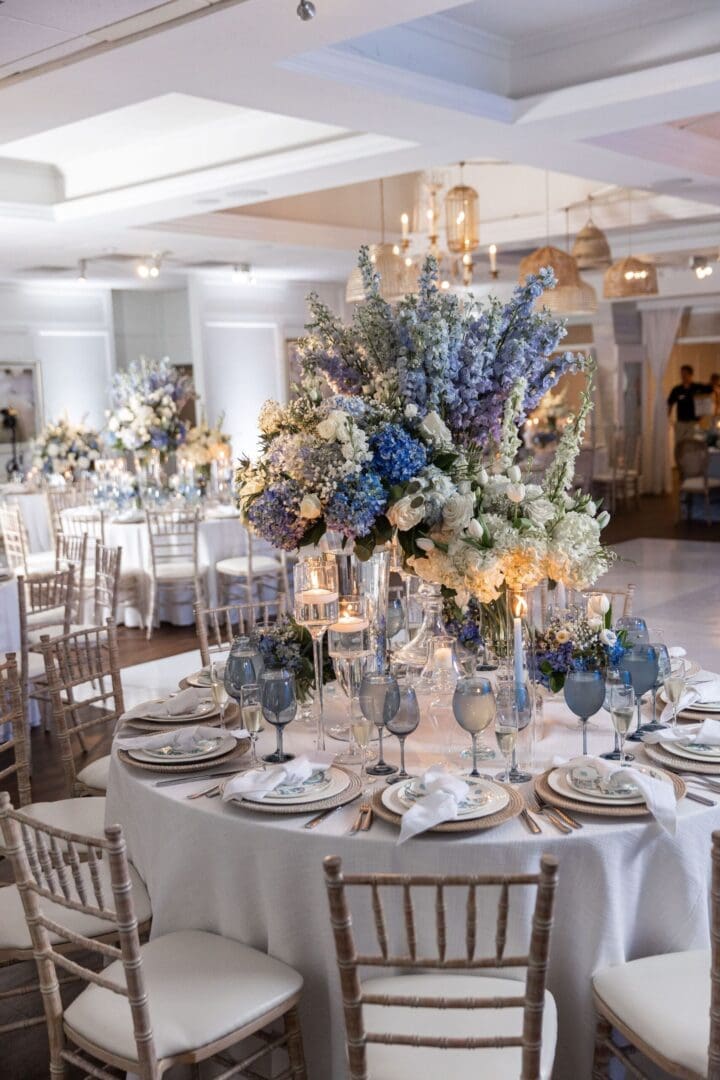 A blue and white wedding table scape with white tables and chairs.