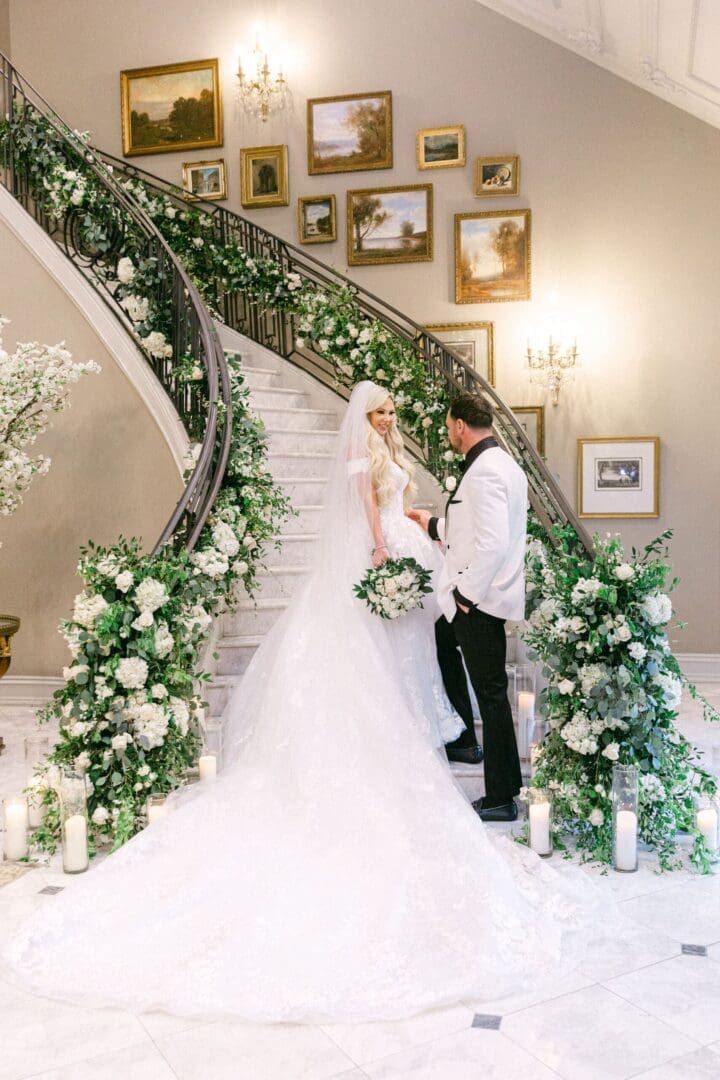 A bride and groom standing on the stairs of a mansion.