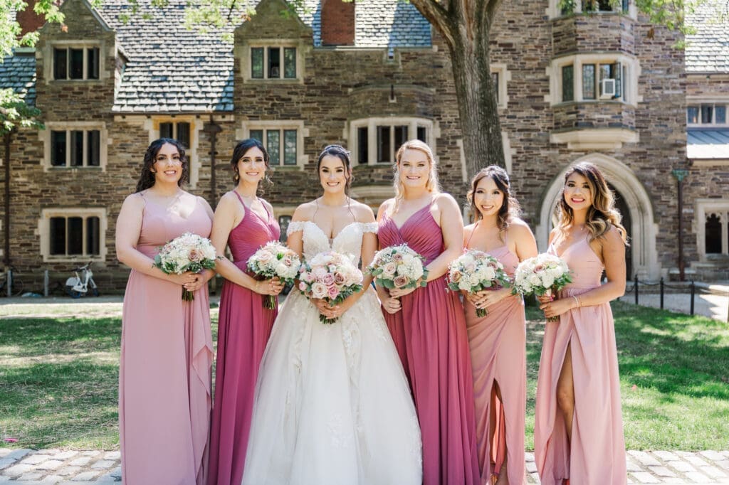 Bridesmaids in pink dresses standing in front of a castle.
