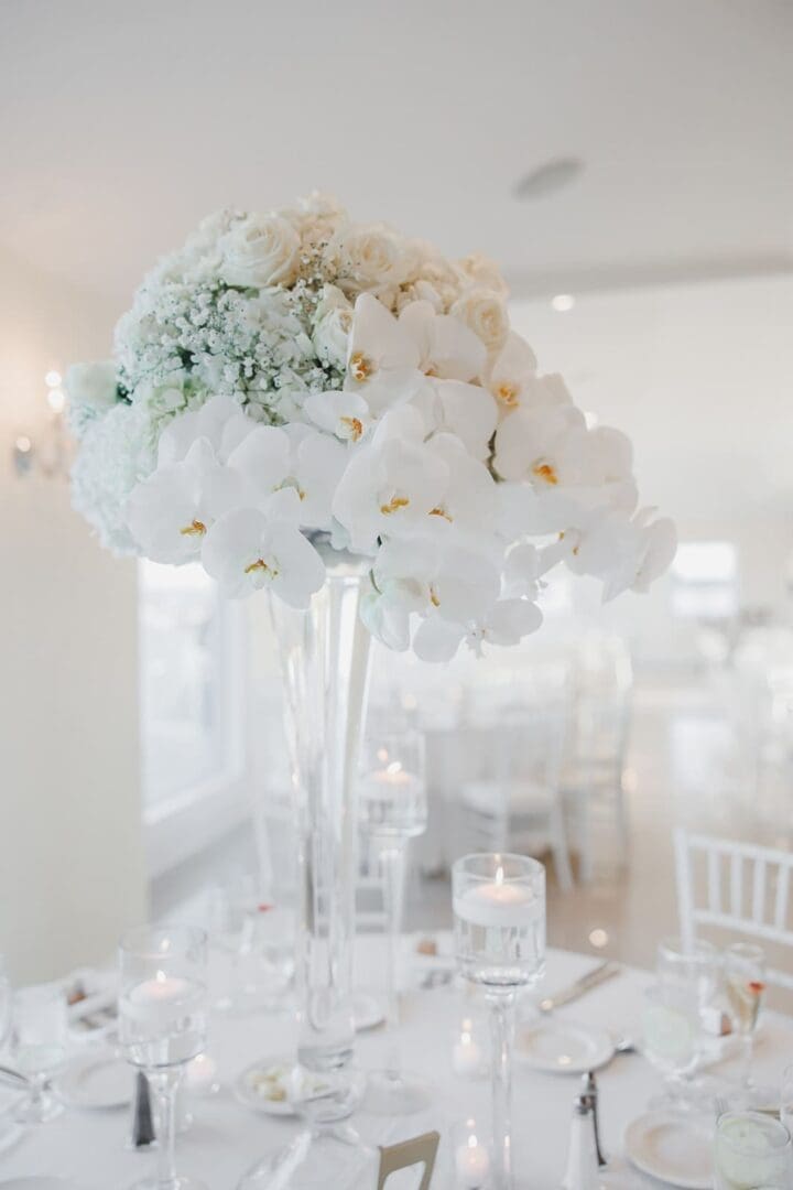 White flowers in a glass vase on a wedding table scape.