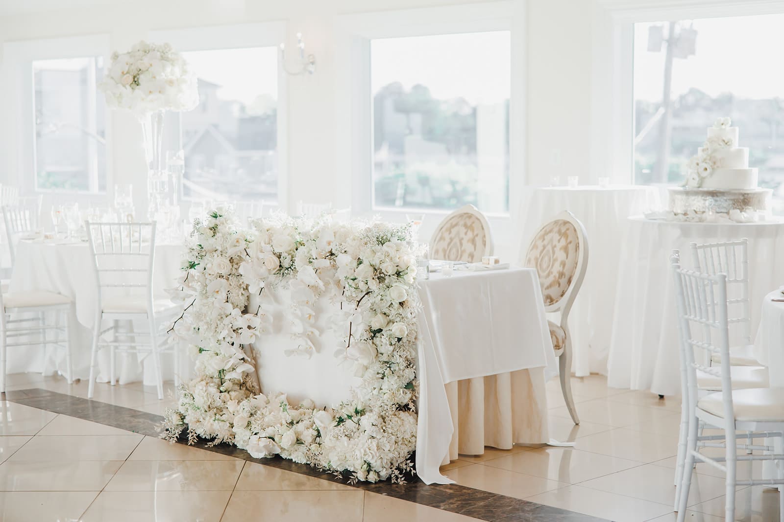 A wedding reception with white flowers and white tables.