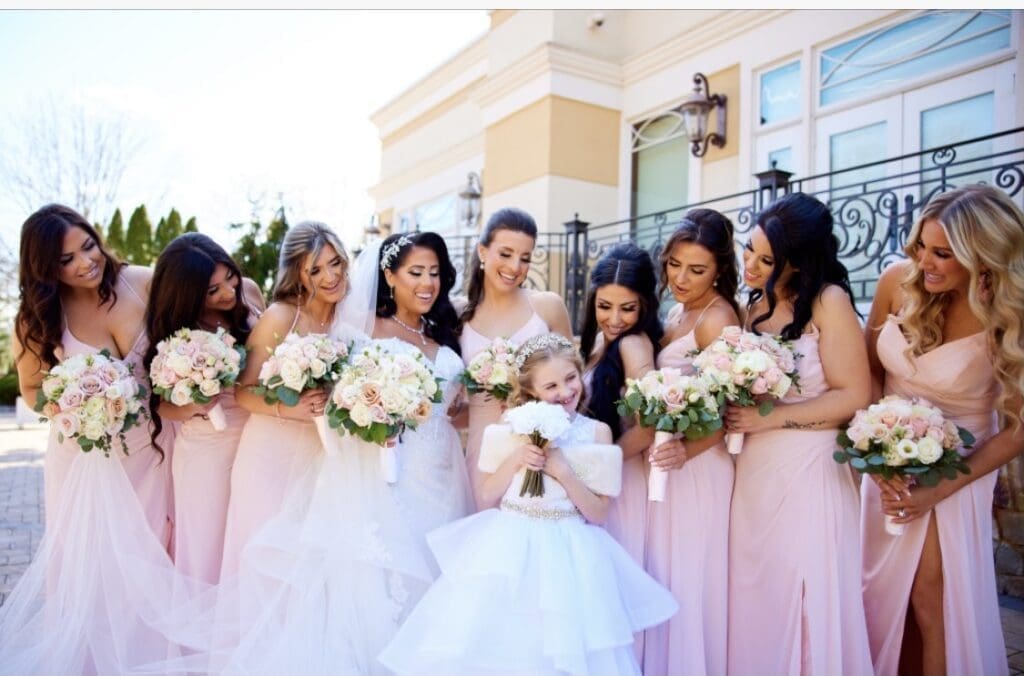 A group of bridesmaids in pink dresses with a little girl.