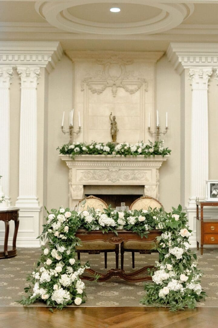 A room decorated with white flowers and a fireplace.