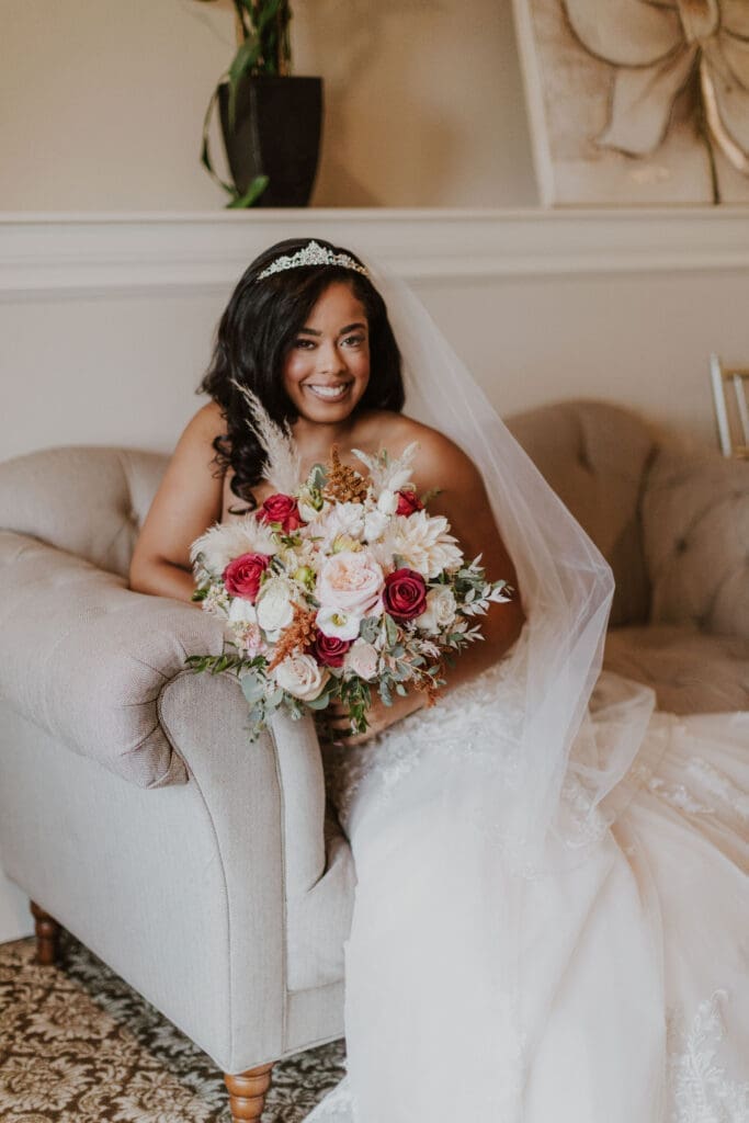 A bride sitting on a couch with her bouquet.