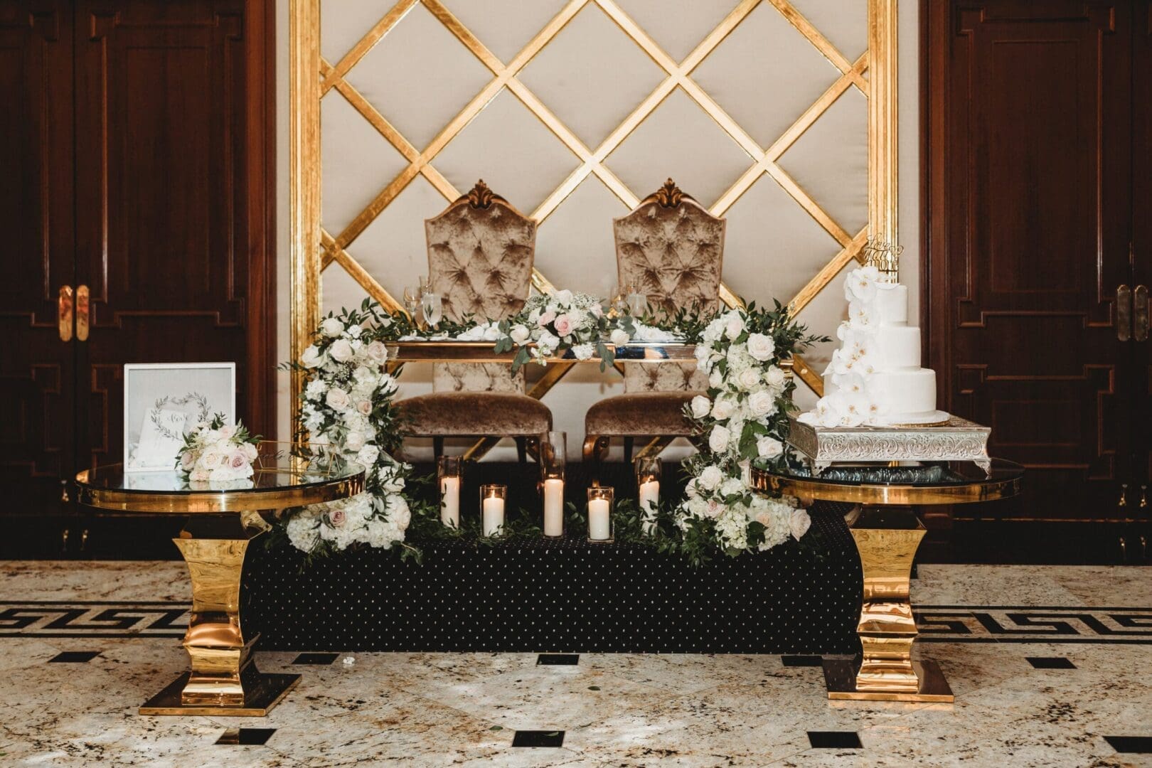 A gold and white wedding table with candles and flowers.