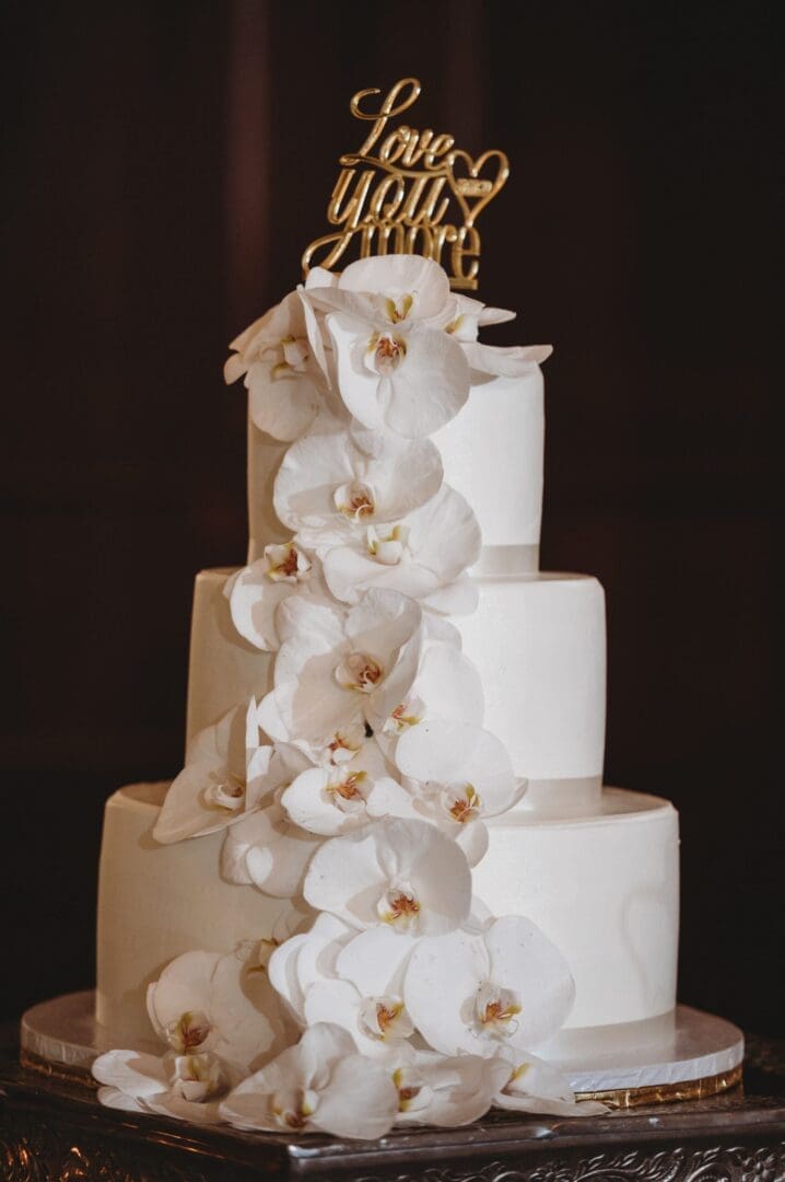 A white wedding cake with orchids on top.