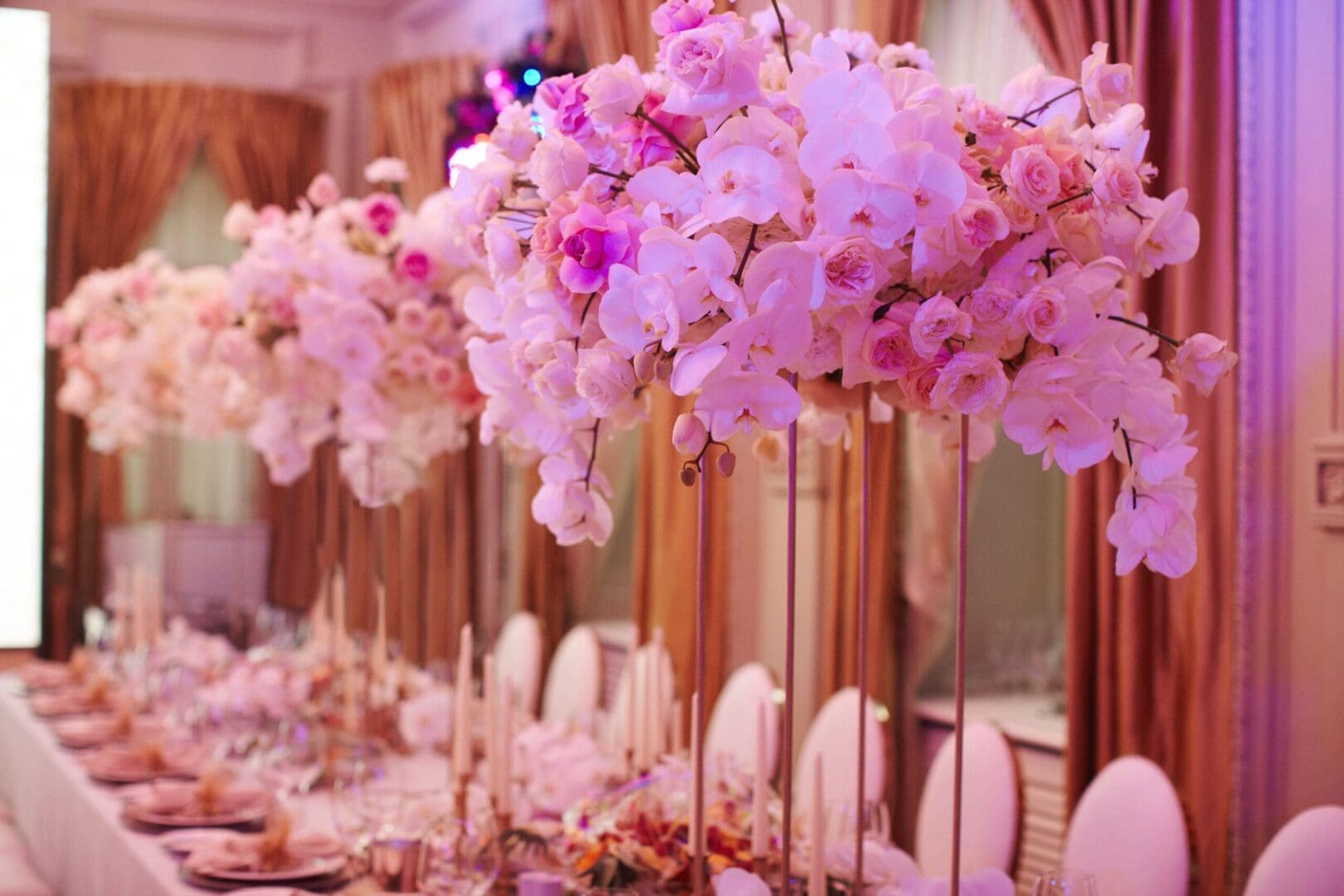 A long table is decorated with pink and white flowers.