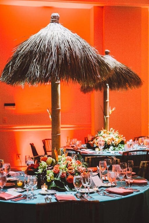 A wedding table scape with a tiki umbrella centerpiece.