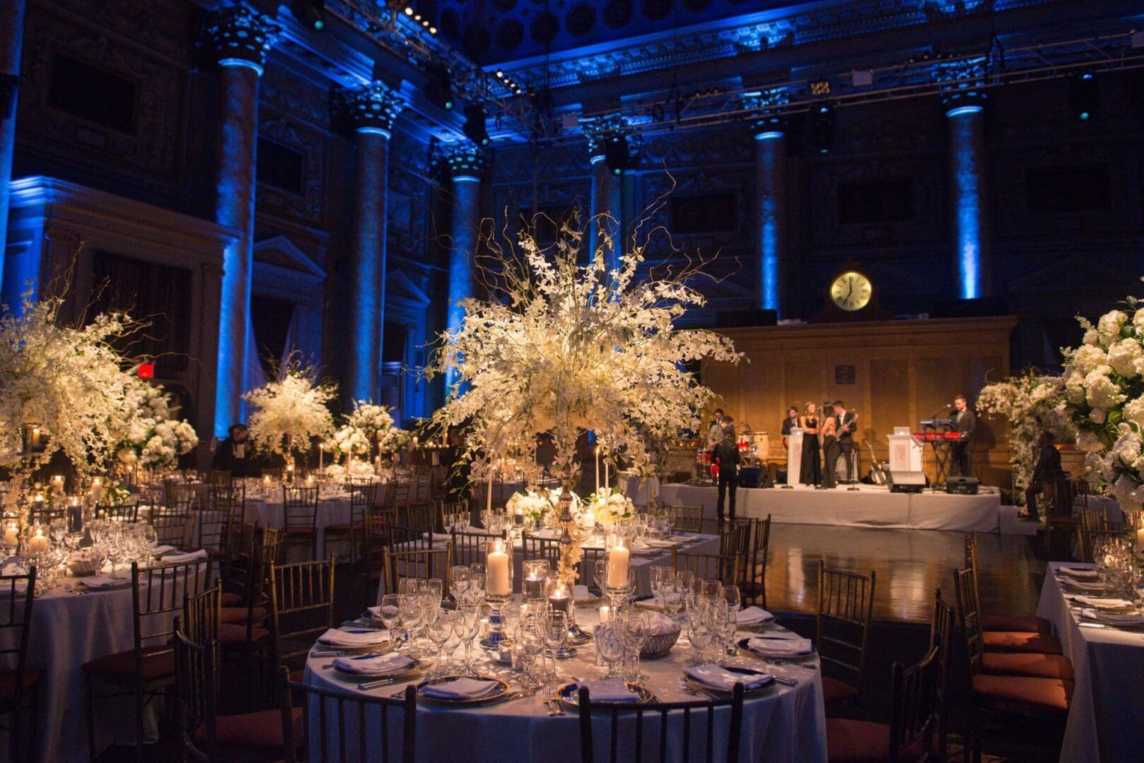 A wedding reception in a large ballroom with enchanting blue lighting and beautifully decorated tablescape ideas.