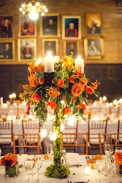An elegant wedding tablescape adorned with orange flowers and candles, creating a beautiful ambiance for the reception.