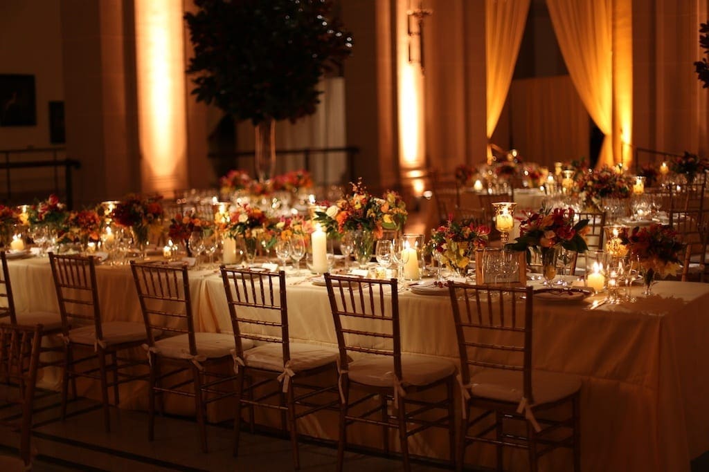A wedding reception table scape set up in a large room with candles.