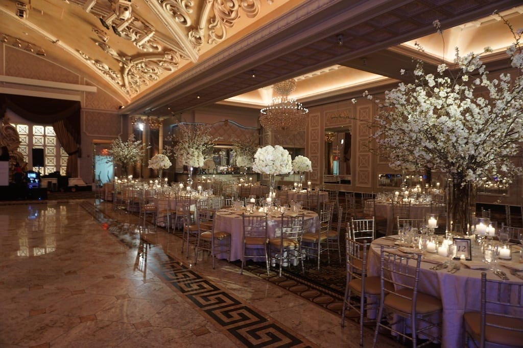 Explore stunning wedding table scape ideas in a grand ballroom adorned with elegant chandeliers.
