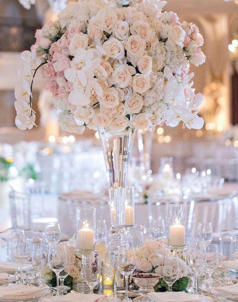 A wedding reception with white and pink flowers in a glass vase, showcasing elegant wedding tablescape ideas.