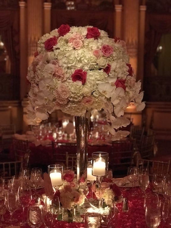 A beautiful wedding tablescape with a stunning centerpiece featuring red and white flowers.