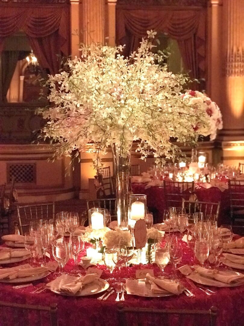 A stunning wedding table scape showcasing a red and white color palette adorned with elegant candles and beautiful flowers.