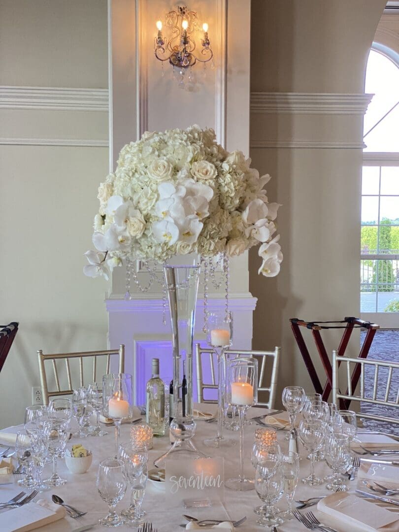 A wedding table scape featuring a glass vase filled with beautiful white flowers.