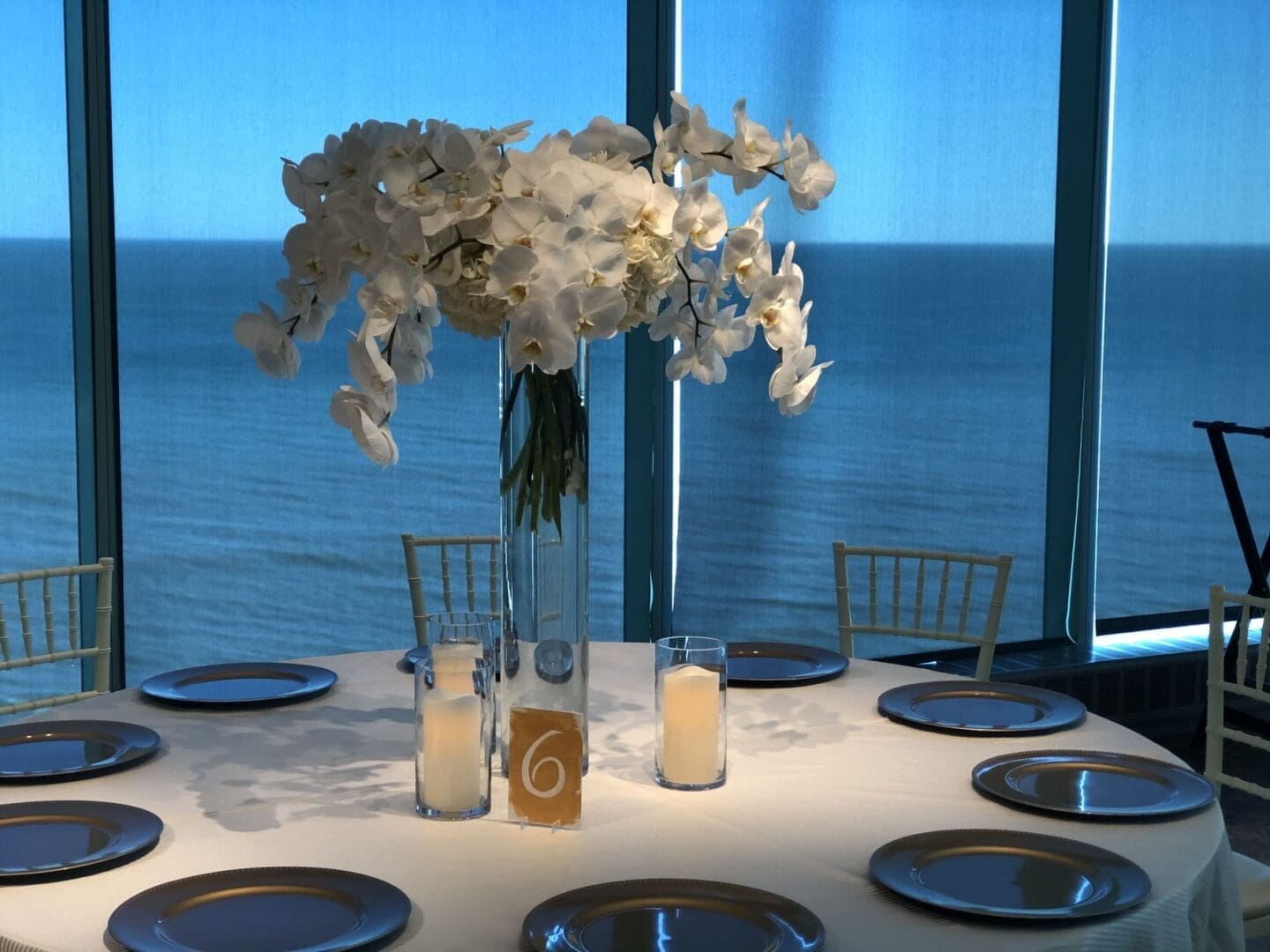 A stunning tablescape featuring a beautiful vase of flowers and a picturesque ocean view, perfect for wedding receptions.
