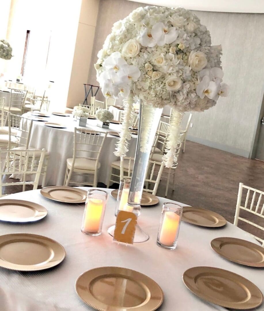 A stunning white and gold table scape with a vase of flowers, perfect for wedding table scape ideas.