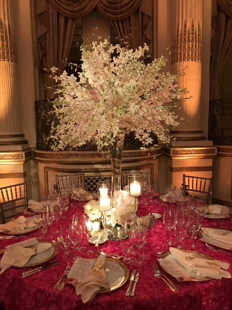 A stunning wedding table scape adorned with beautiful flowers and glowing candles, elegantly arranged in a grand room.