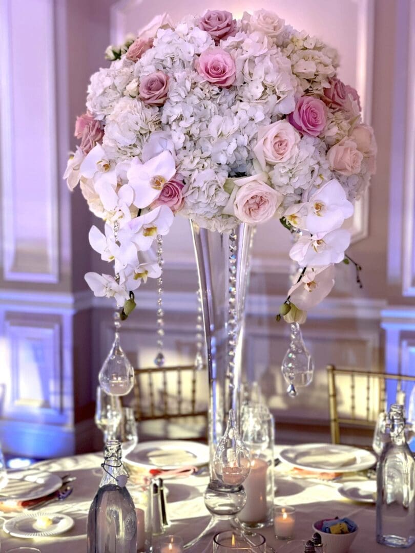 A stunning wedding centerpiece featuring pink and white flowers arranged in a tall vase.