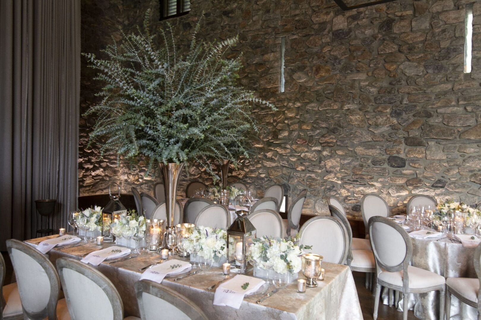 A wedding reception set up in a stone room, featuring enchanting wedding table scape ideas.